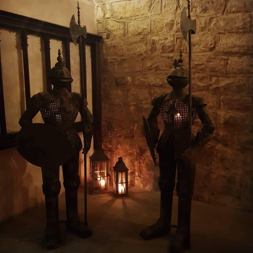 Two metal knights with candles in their armour and lanterns behind them.