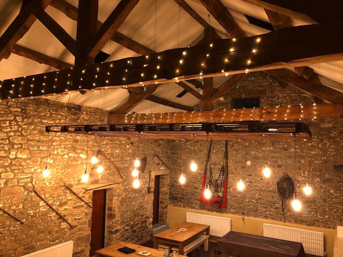 Light bulbs hanging down from a pallet lighting piece in an old barn.